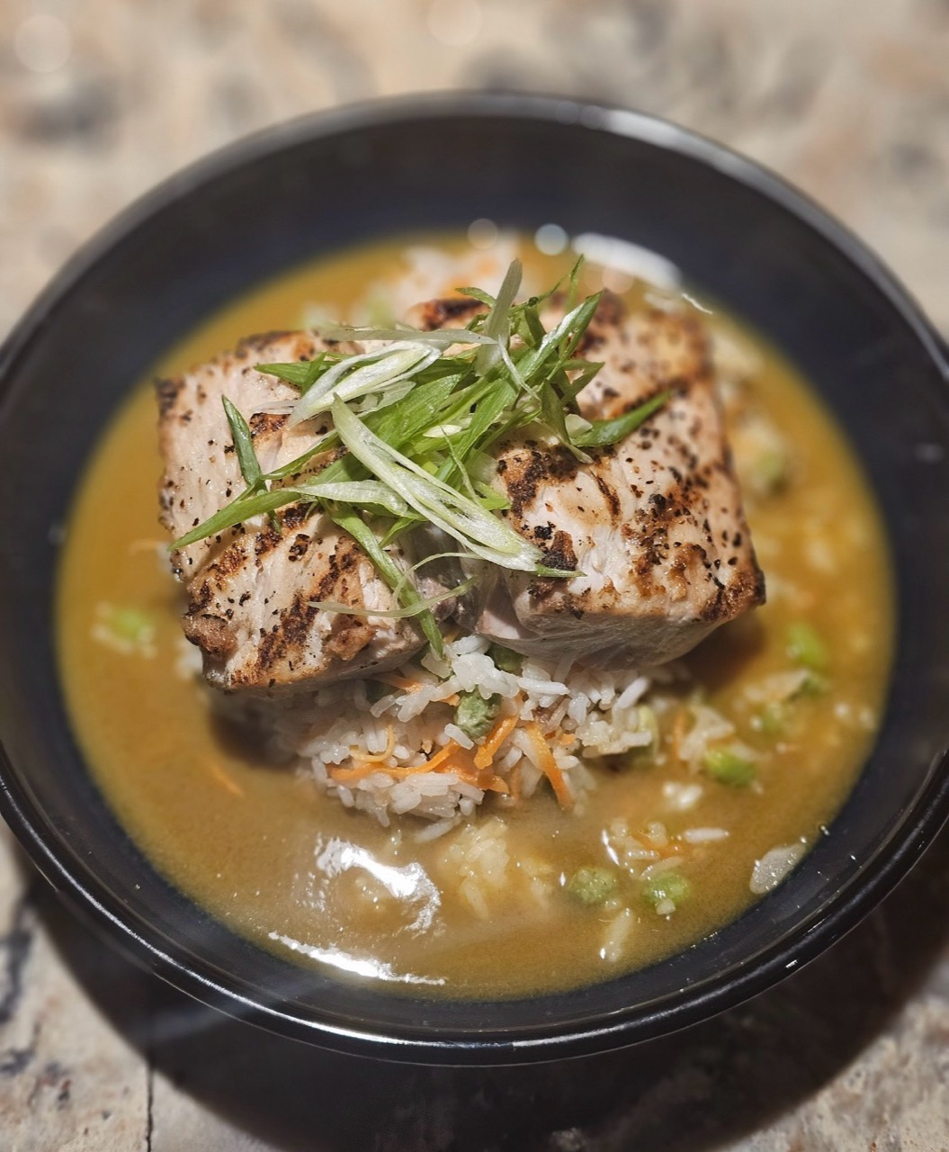 Grilled fish served over rice with scallions