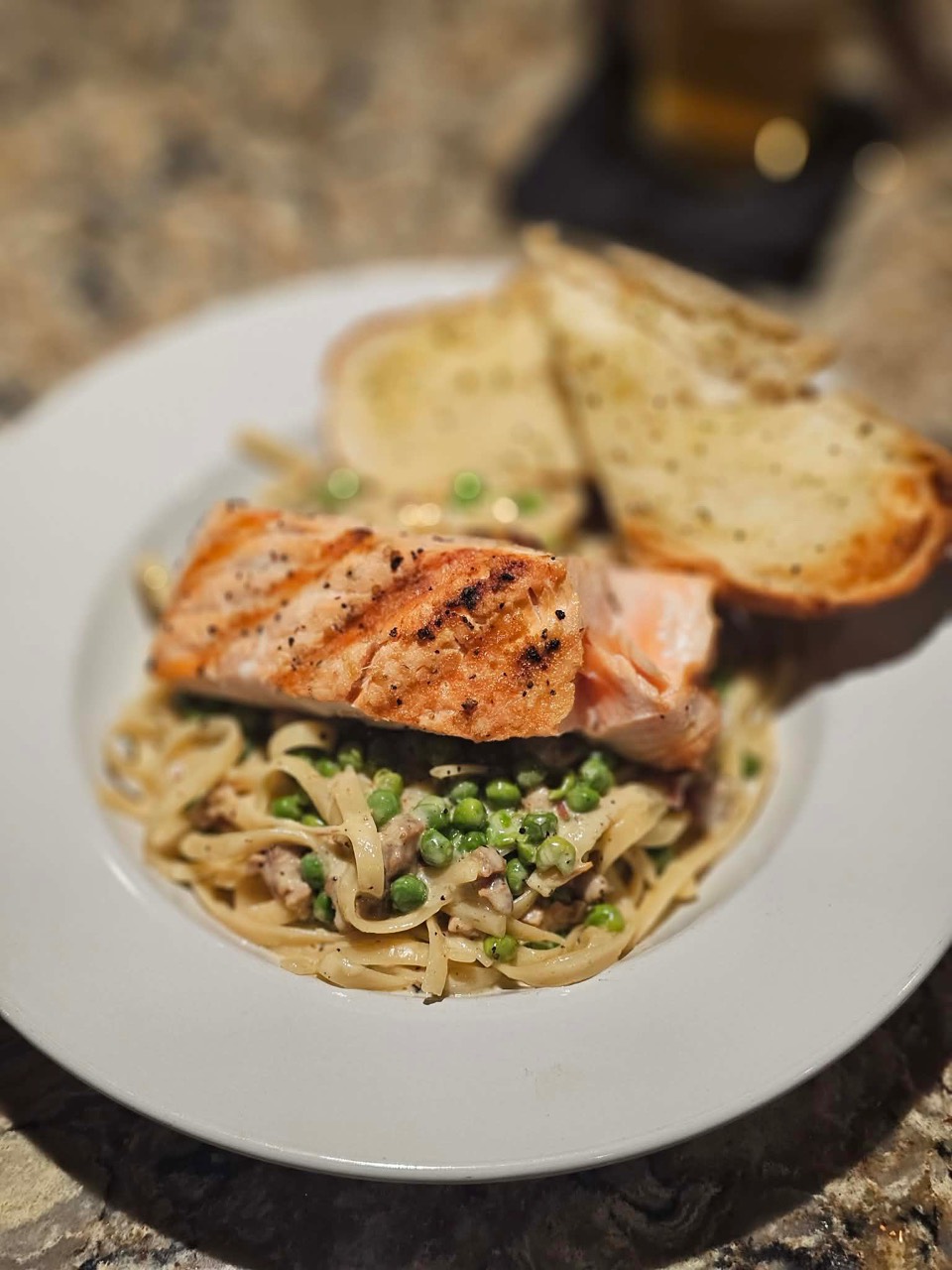 Grilled salmon served over creamy pasta with peas